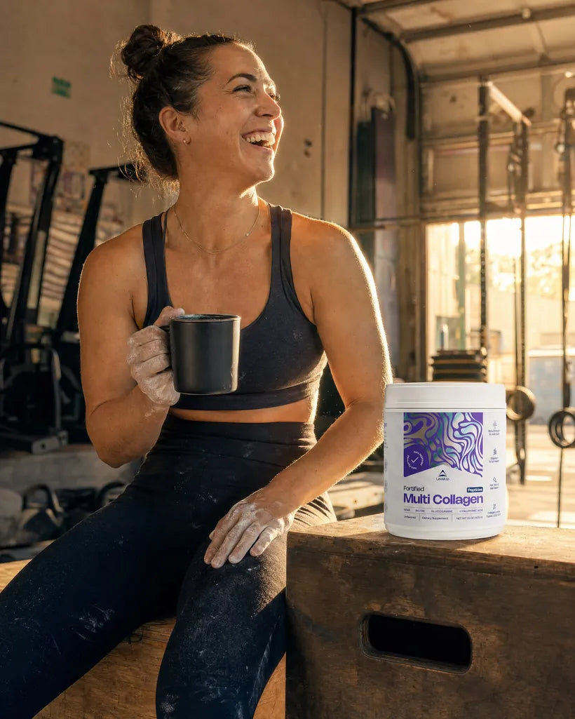 An athlete laughs on a plyo box at sunrise with a tub of Fortified Multi Collagen beside her